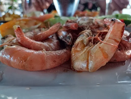 Teller mit frisch zubereiteten Garnelen, begleitet von Gemüse und Gewürzen, serviert in einem Restaurant